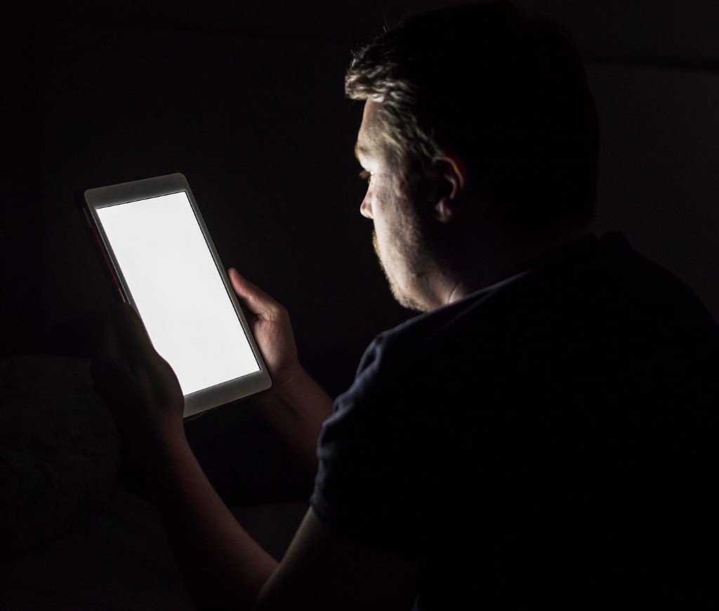 Assessor holding a bright tablet in a dark cab.